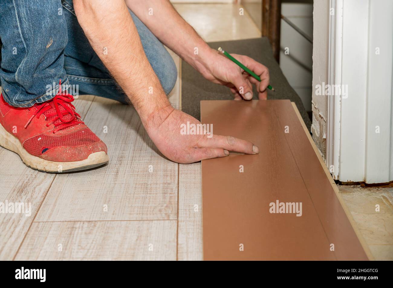 Schmutzige Hand einer Person, die mehrere Finger amputiert hat. Person mit schmutzigen Kleidern, die einen Boden in seinem Haus legt. Stockfoto