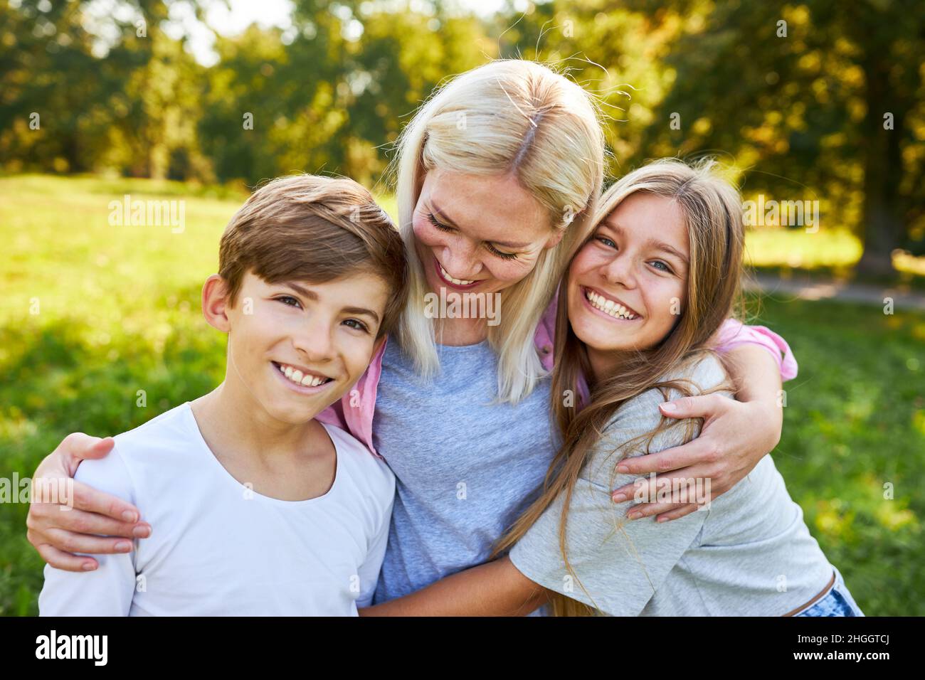 Mutter und ihre glücklichen Kinder umarmen sich im Sommer im Garten Stockfoto