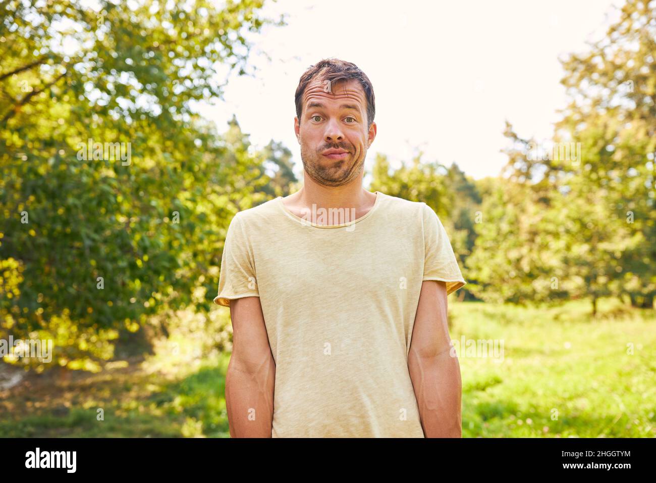 Der Mensch steht im Sommer in der Natur auf einer Wiese und macht eine lustige Grimasse Stockfoto