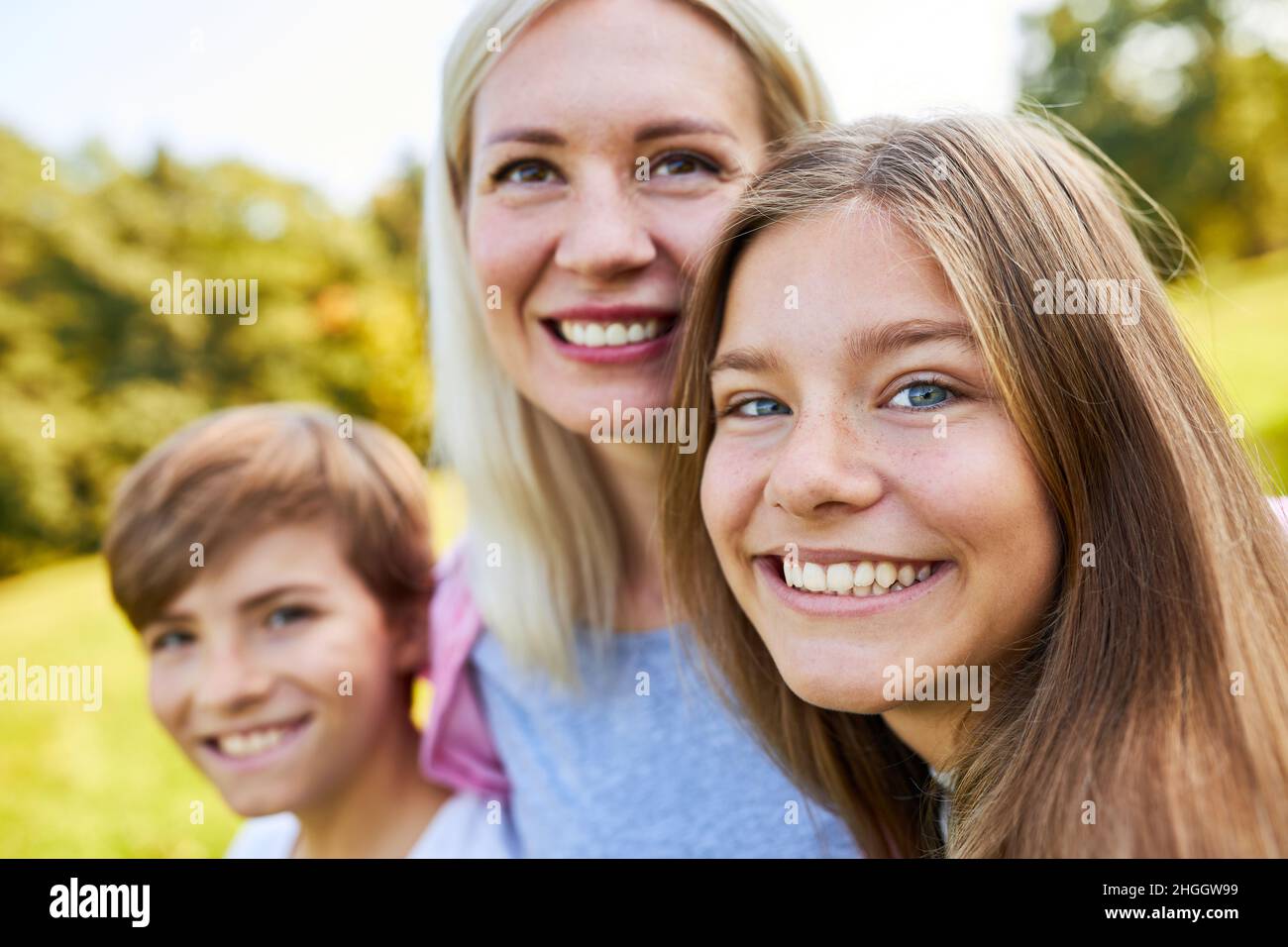 Glückliche Kinder und ihre lächelnde Mutter im Sommer gemeinsam im Park Stockfoto