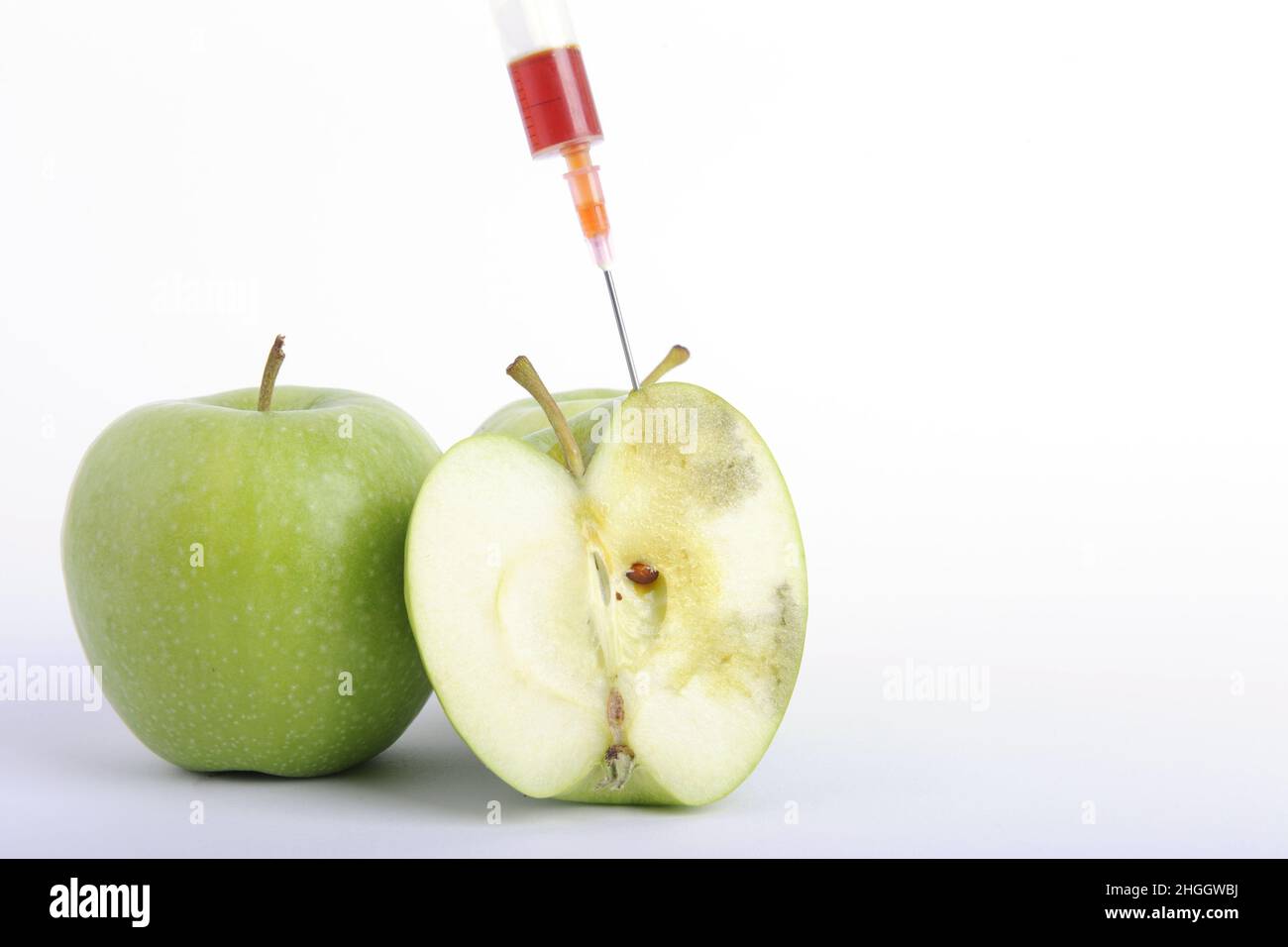 apfel (Malus domestica), Spritze klebt in einem halbierten Apfel, genetisch manipuliertes Essen Stockfoto