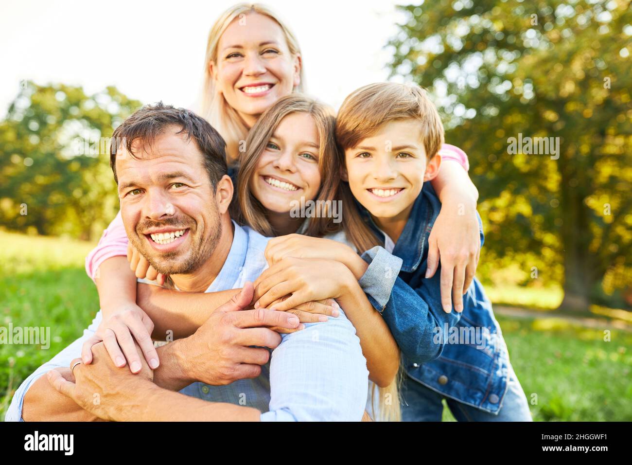 Glückliche Familie mit Eltern und zwei Kindern zusammen im Garten im Sommer Stockfoto