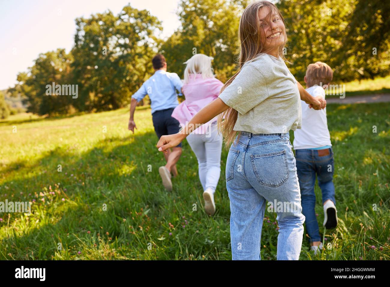 Teenager, der im Sommer mit Eltern und Bruder über eine grüne Wiese läuft Stockfoto