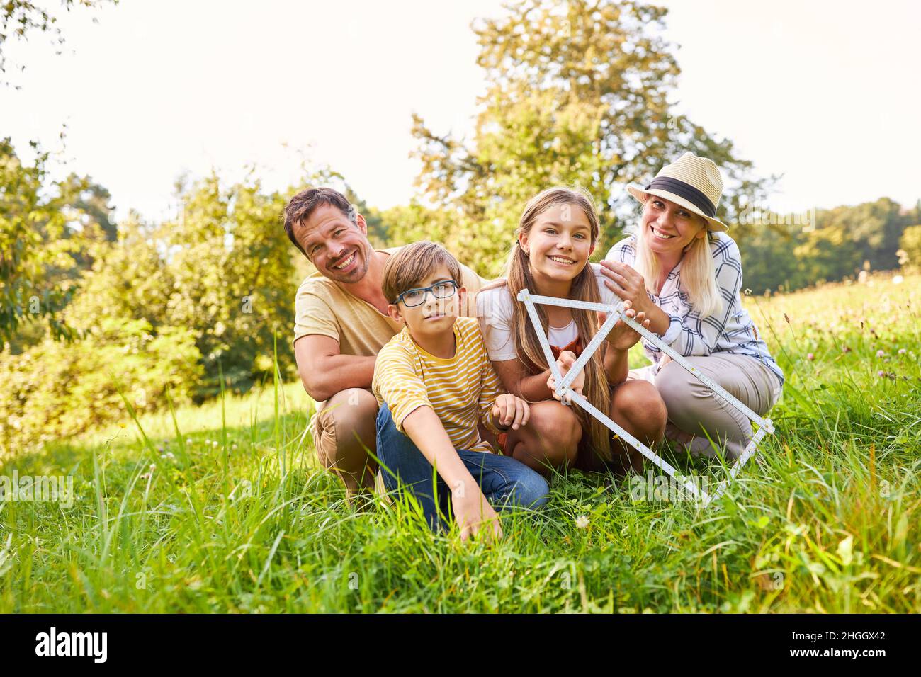 Glückliche Familie mit einem Haus Klapplineal im Park im Sommer für die Heimplanung Stockfoto