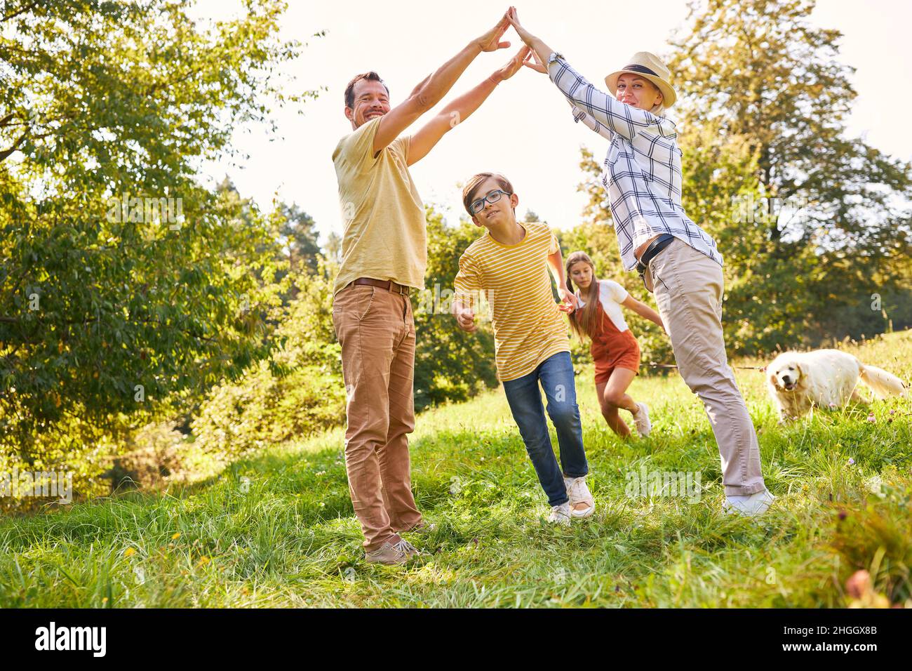 Kinder in einem Rennen durch ein Tor von den Händen der Eltern in der Natur im Park gebildet Stockfoto