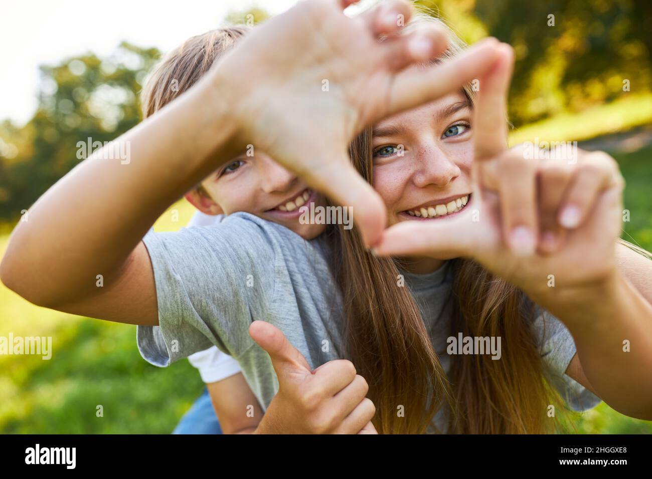 Bruder und Schwester bilden mit ihren Händen ein Quadrat, während sie in der Natur spielen Stockfoto