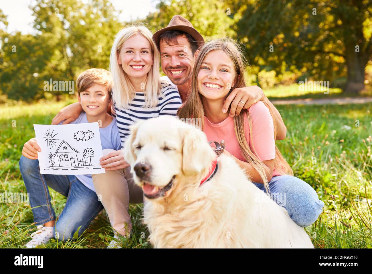 Glückliche Familie mit zwei Kindern und Hund mit Zeichnung des Traumhauses der Zukunft Stockfoto