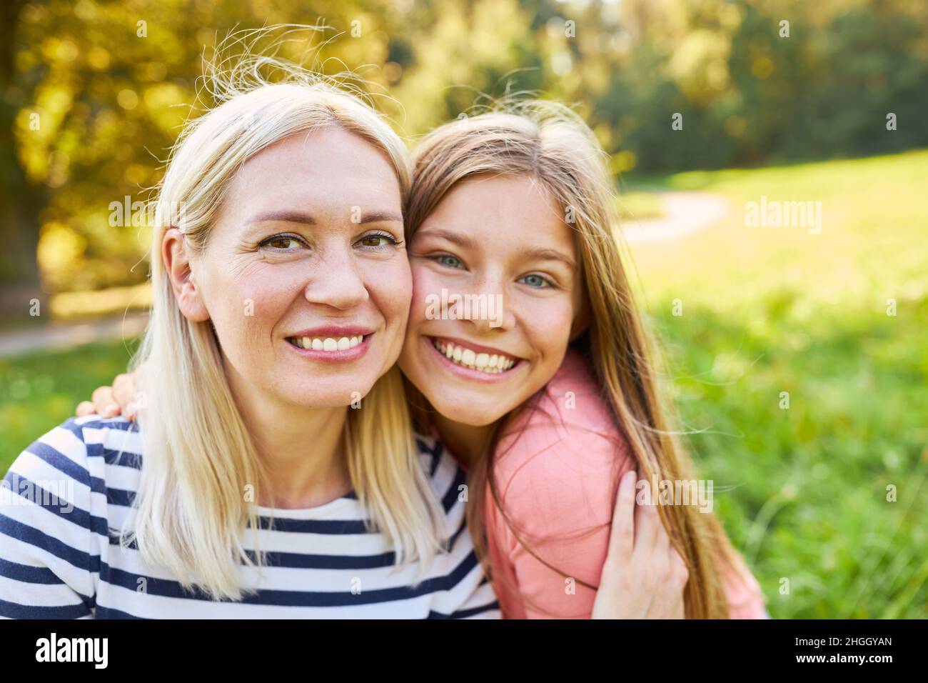 Glückliche Mutter und Tochter umarmen sich im Sommer liebevoll in der Natur Stockfoto