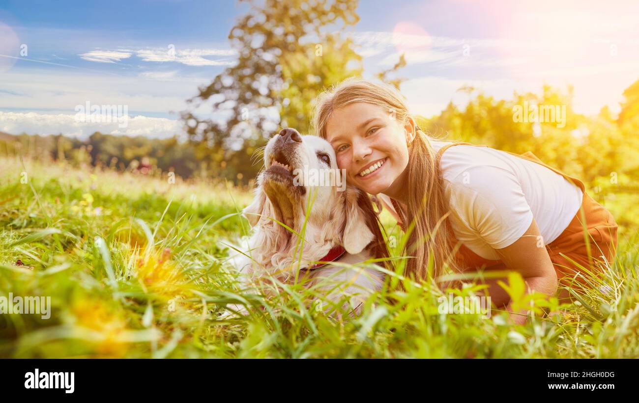 Glückliches Mädchen kuschelt im Sommer mit ihrem Hund im Garten Stockfoto