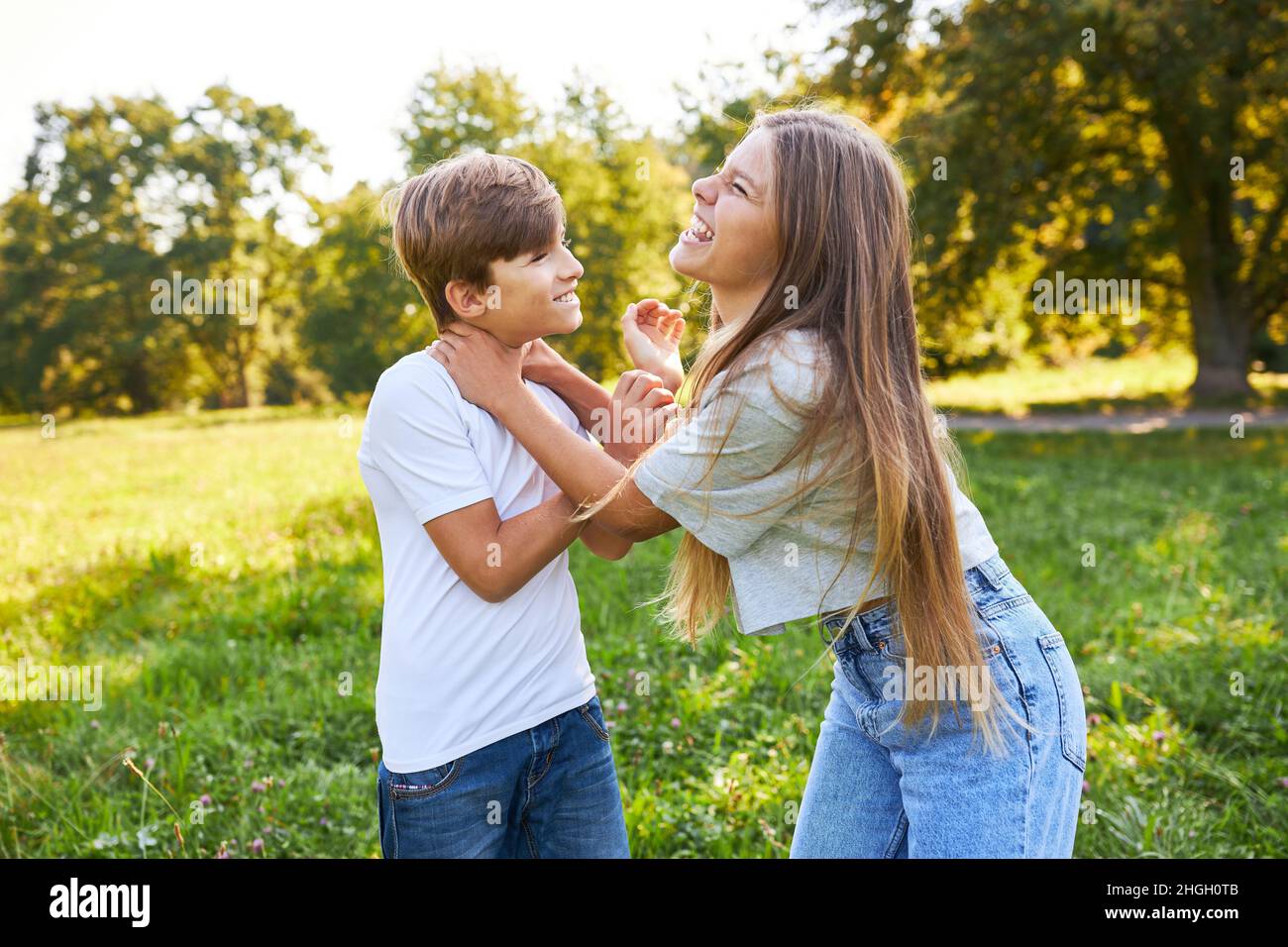 Bruder und Schwester zangeln und kämpfen im Sommer im Park im Urlaub Stockfoto