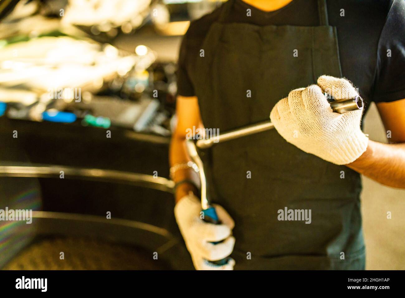 lateinischer hispanischer Automechaniker in Uniform untersucht ein Auto, während er im Autodienst arbeitet Stockfoto