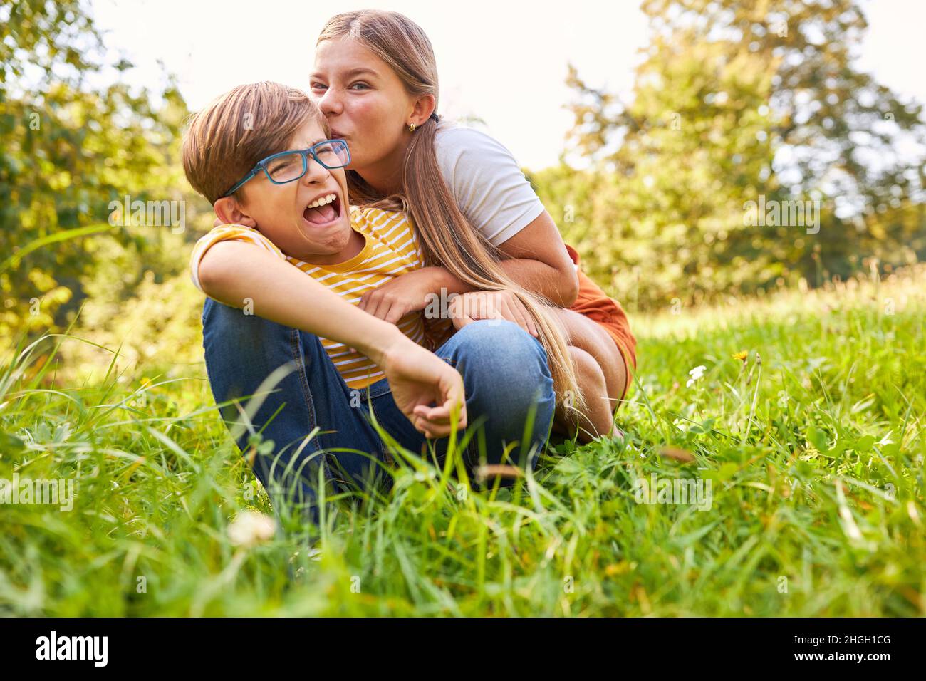 Schwester neckt ihren Bruder im Sommer auf einer Wiese in der Natur Stockfoto