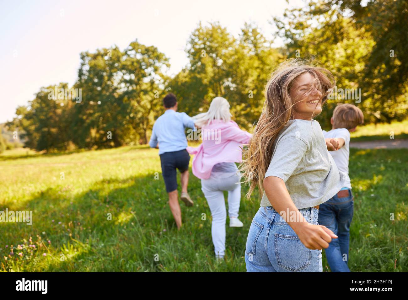 Glückliche Familie in Bewegung auf einer grünen Wiese im Sommer in der Natur Stockfoto