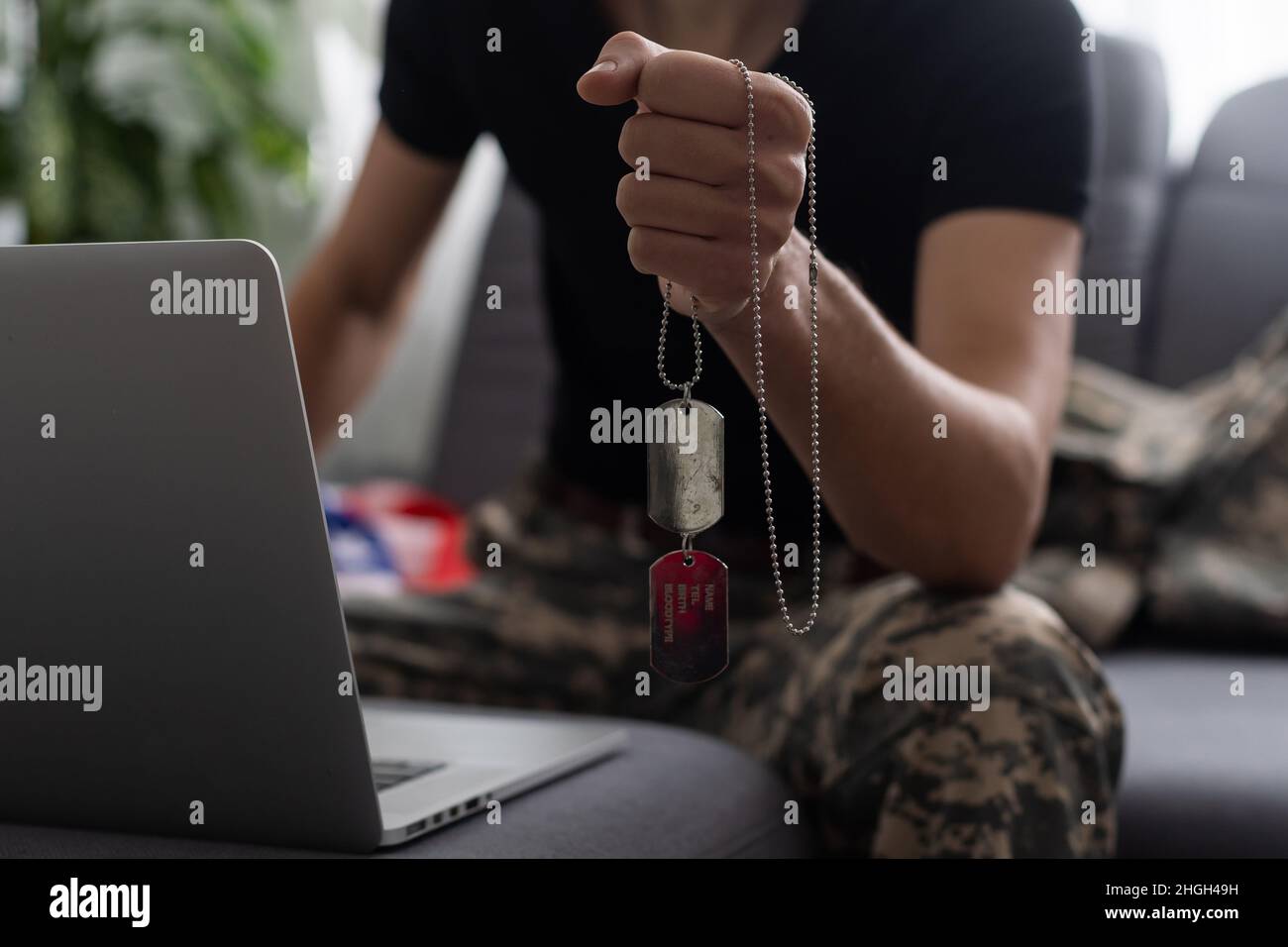 Patriotischer Militärangehöriger im Headset, der in der Nähe der amerikanischen Flagge auf einen Laptop schaut Stockfoto