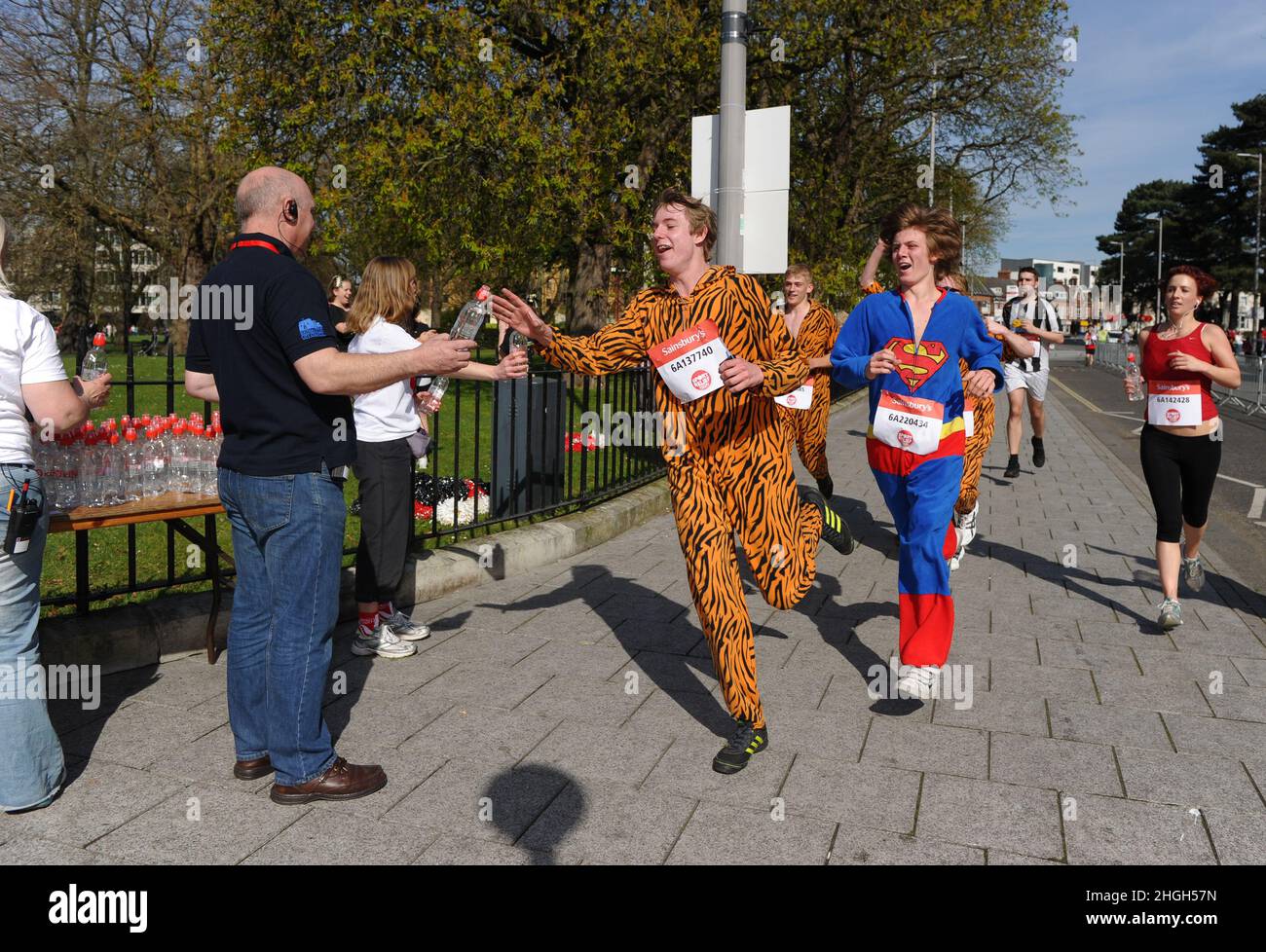 Ein Mann, der in einem Tiger-Body-Anzug gekleidet ist, ergreift während des Sport Relief Run in Southampton am 25th. März 2012 Wasserflaschen von der Wasserstation. Stockfoto