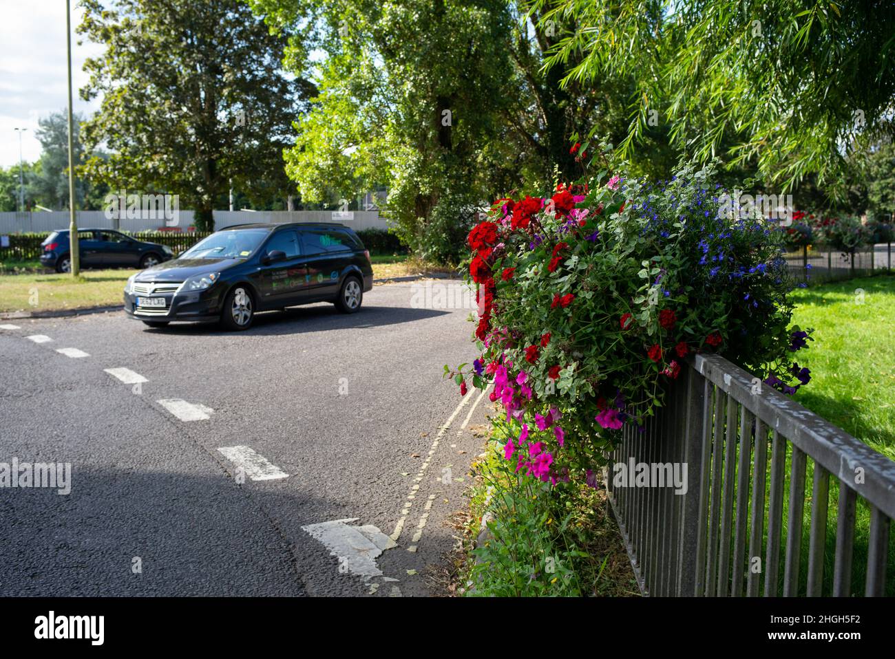 Der Kreisverkehr in die Marktstadt Romsey, Hampshire England, hat eine farbenfrohe Ausstellung von Blumenkästen/ Körben auf den umliegenden Zäunen. Stockfoto