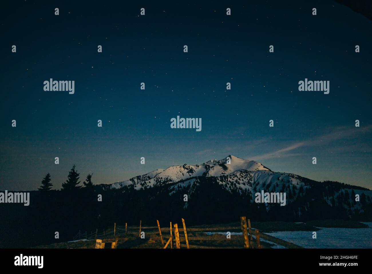 Verschneite Wiese, verschneite Berge und Sterne im Hintergrund Stockfoto