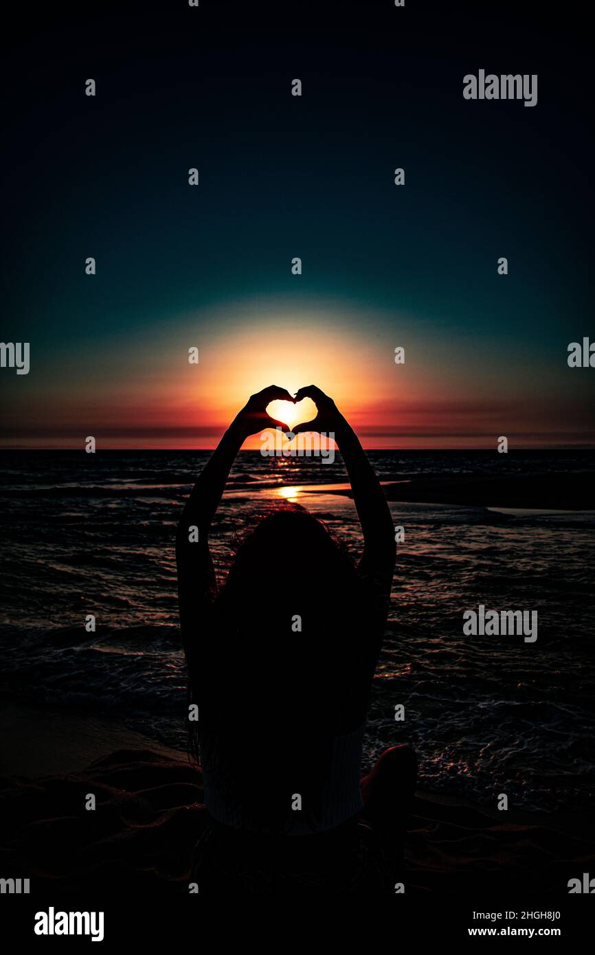 Handmodell ein Herz unter der Sonne zu machen unterging mit der Sonne in der Mitte Stockfoto