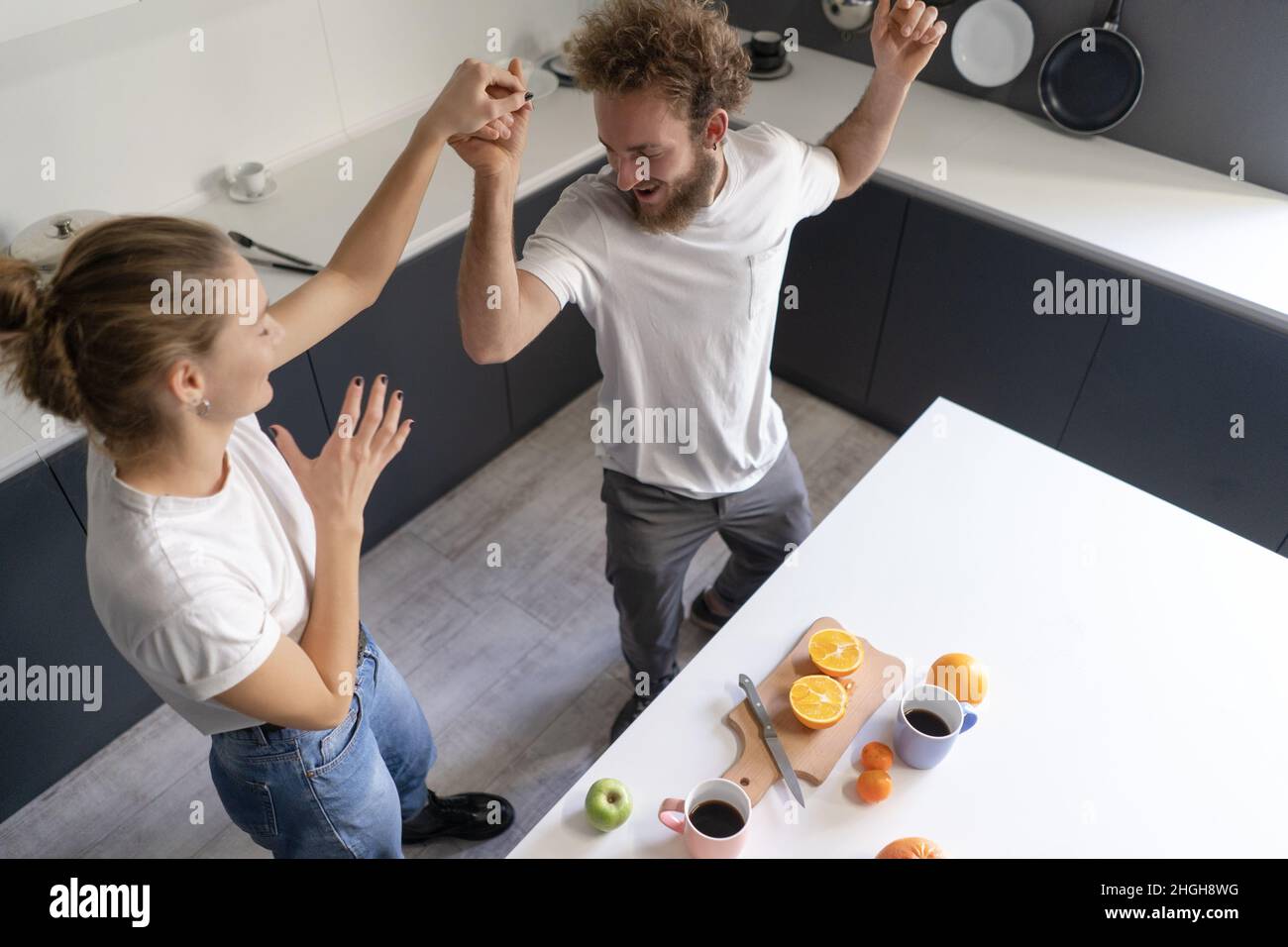 Walzing in einem neuen Zuhause junges Paar tanzen ihren neuen Kauf des eigenen Hauses zu feiern. Eine glückliche neue Familie in der Küche trägt legere Kleidung. Liebe, Familie, Glück Konzept. Hochwertige Fotos Stockfoto