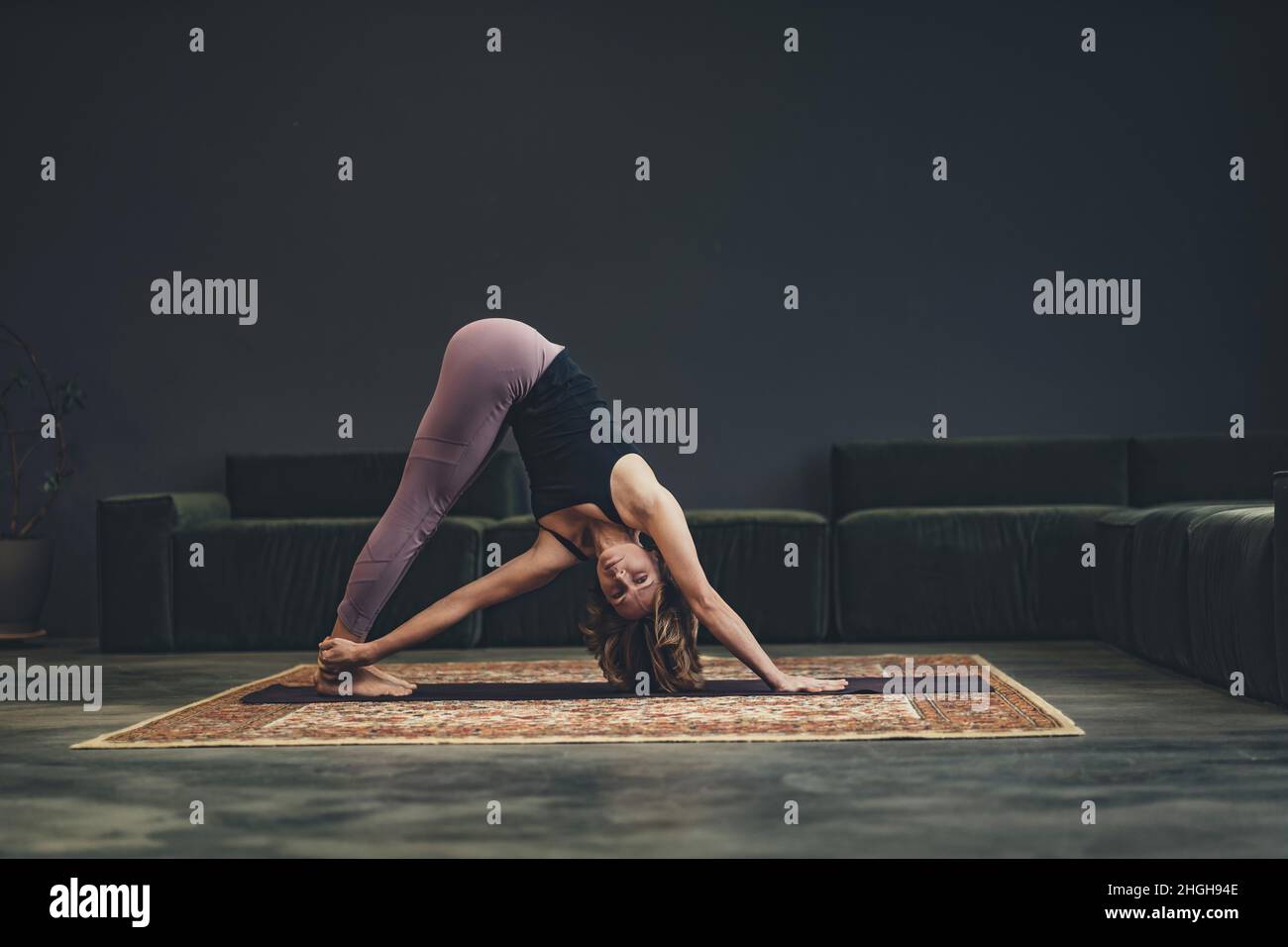 Lächelnde junge Frau auf einer Matte tut ein Asana. Konzept des Yoga in der Stadt. Gesundheit, Langlebigkeit, schlanke Figur. Hochwertige Fotos Stockfoto