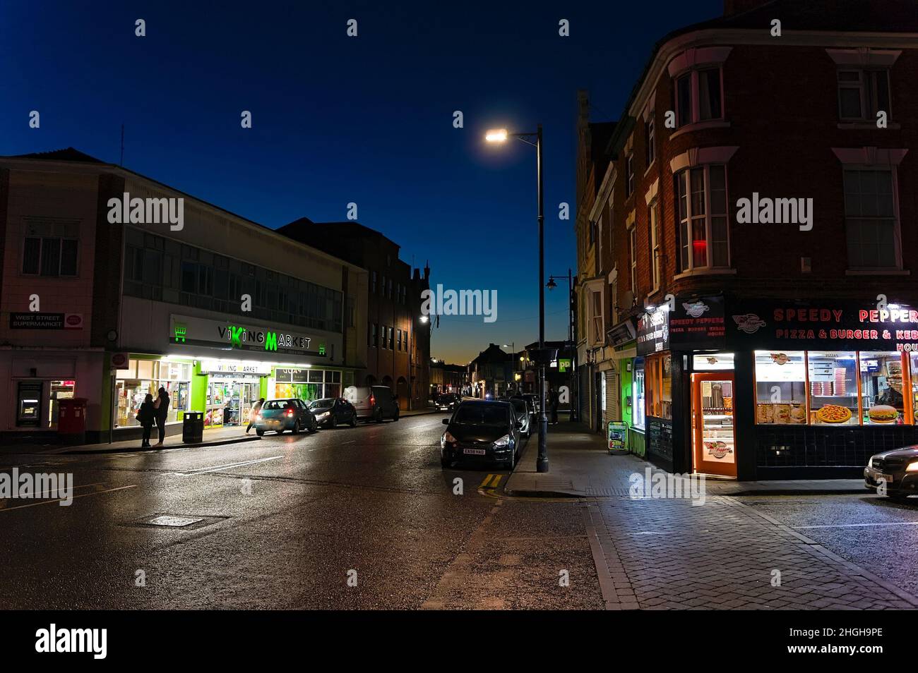 Blick auf beleuchtete Geschäfte und Imbissbuden auf der West Street am Abend Stockfoto