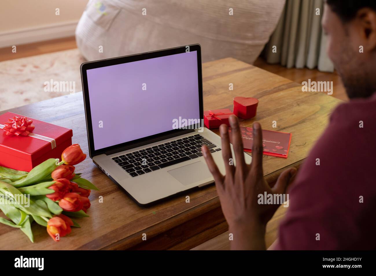 afroamerikanischer Mann winkt über den Laptop über den videoanruf von valentine und zeigt den Kopierplatz Stockfoto