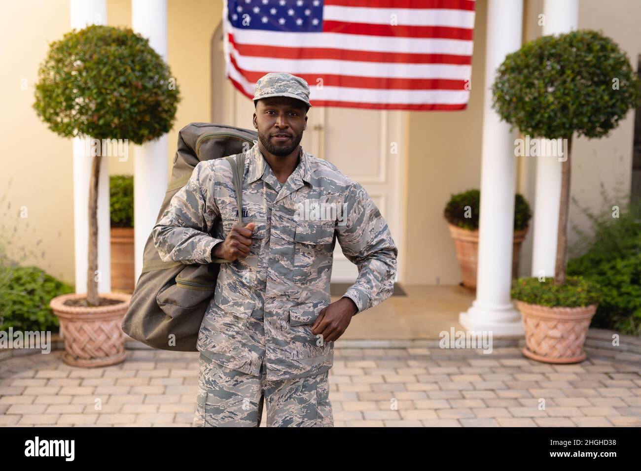 Porträt eines selbstbewussten männlichen afroamerikanischen Soldaten mit Tasche vor dem Hauseingang Stockfoto