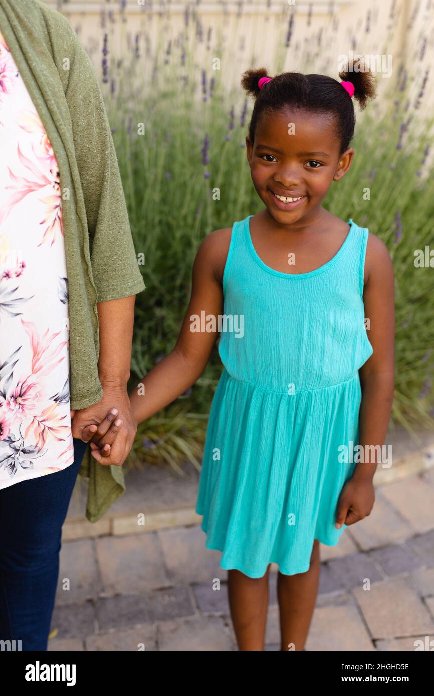 Porträt eines afroamerikanischen Mädchens, das die Hände ihrer Enkelinnen hält, während es im Freien steht Stockfoto