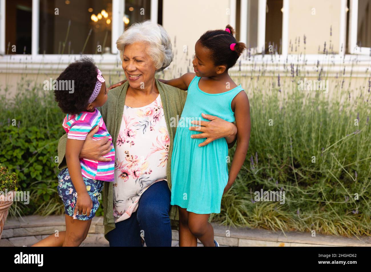 afroamerikanische Großmutter, die ihre Enkelinnen ansah und im Freien lächelte Stockfoto
