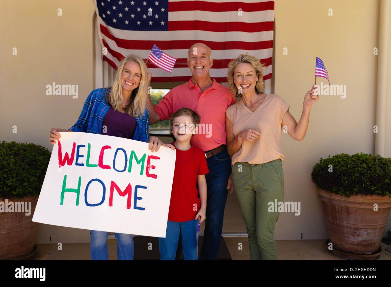 Porträt der glücklichen kaukasischen Familie usa Flaggen und willkommen zu Hause Plakat steht am Eingang Stockfoto