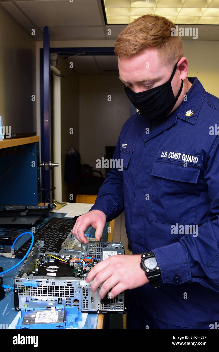 US Coast Guard Petty Officer 2nd Class Cody Whitt, ein Informationssystemtechniker (IT), der der Abteilung Electronics Support Jacksonville, Florida, zugewiesen wurde, führt bei der Küstenwache am 20. Januar 2022 eine Fehlersuche für einen Desktop-Computer durch. Das ITS ist für die Einrichtung und Wartung von Computersystemen der Küstenwache sowie analogen und digitalen Sprachsystemen sowie für die Installation und Wartung der physischen Netzwerkinfrastruktur verantwortlich, die diese Systeme miteinander verbindet. Stockfoto