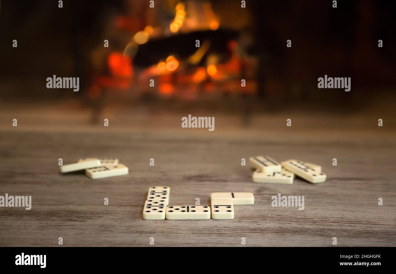 Dominospiel im Winter am Kamin auf einem Holztisch, keine Person. Stockfoto