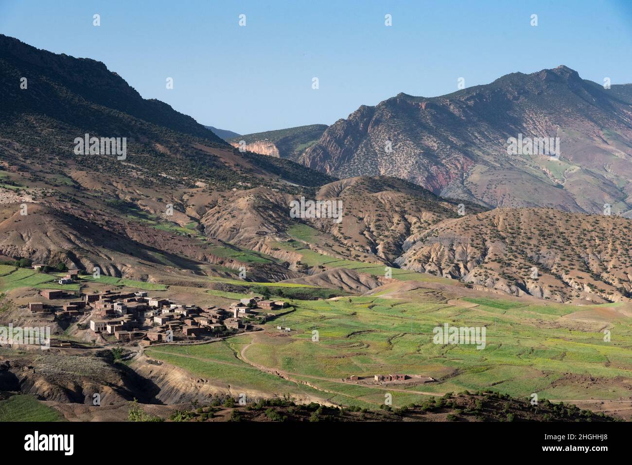 Das Atlasgebirge in Marokko. Berber Dorf am Fuße eines Tals, umgeben von terrassenförmigen Pflanzen Stockfoto