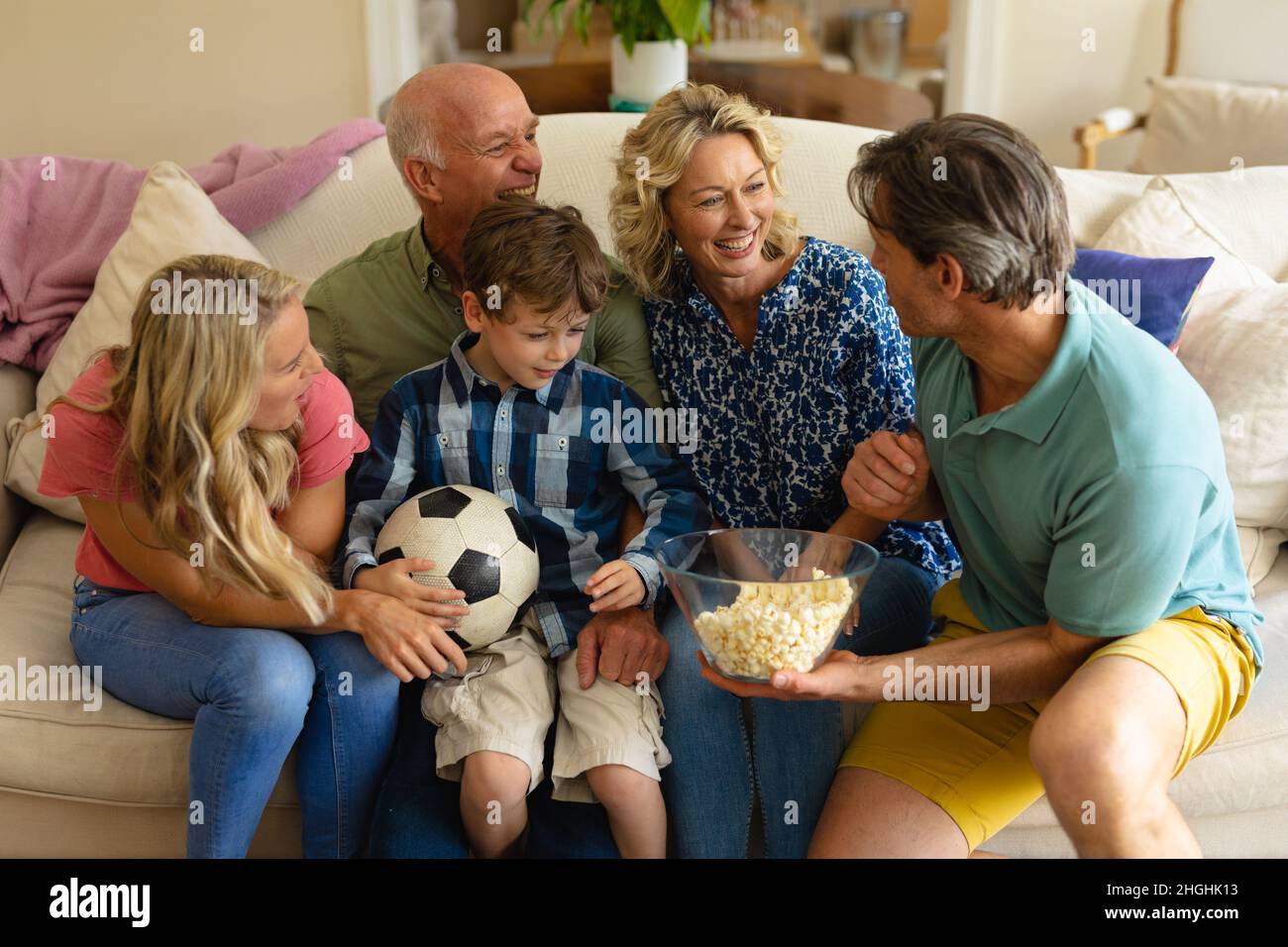 Kaukasische Familie in drei Generationen, die gemeinsam auf der Couch zu Hause Fernsehen Stockfoto