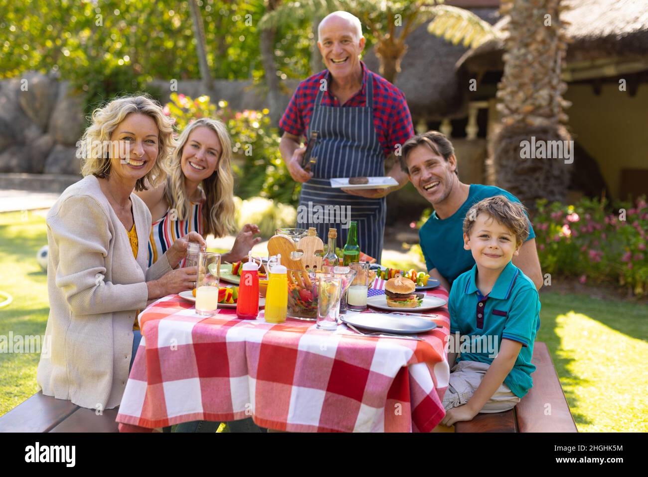 Porträt eines lächelnden kaukasischen Familie aus drei Generationen, die im Garten Grillgerichte isst Stockfoto