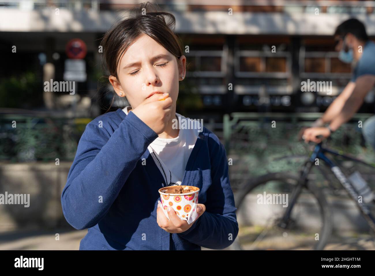 Kinder essen Eisbecher unter der Sonne. Kleines Mädchen genießen süße Schokolade Dessert an sonnigen Tag im Freien Stockfoto