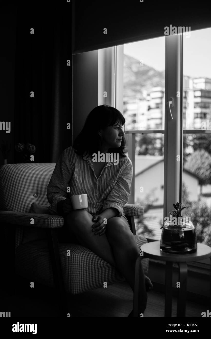 Schwarz-Weiß-Porträt einer jungen Frau, die zu Hause Morgenkaffee trinkt Stockfoto
