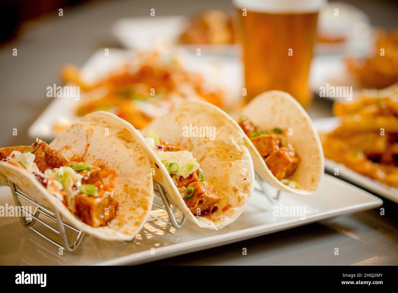 Tofu Trio von Tacos mit Bier im Hintergrund Stockfoto