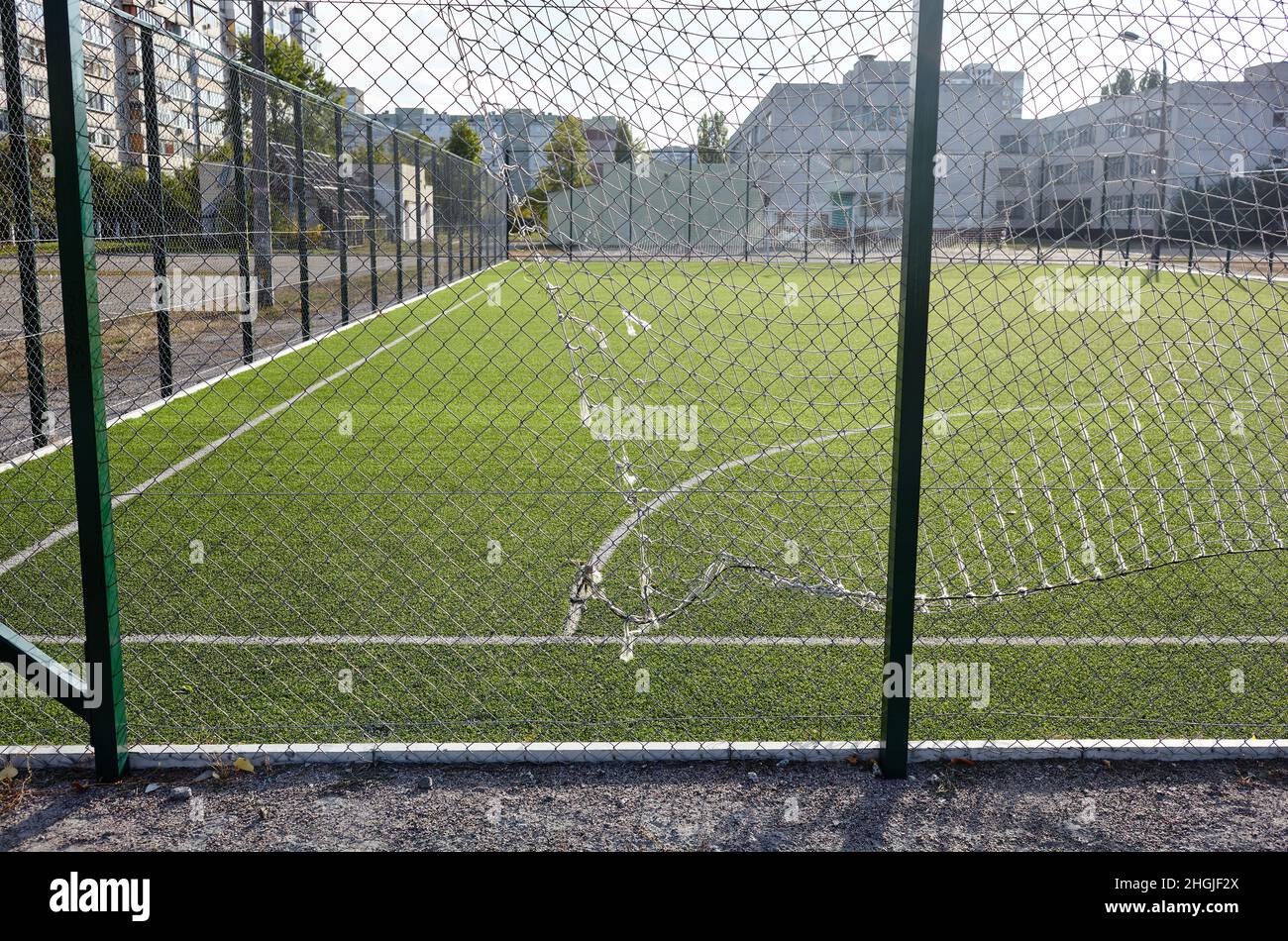 Rasenplatz zum Fußballspielen hinter dem grünen Zaun Mesh. Nahaufnahme des Fußballfeldes mit grünem Gras Stockfoto