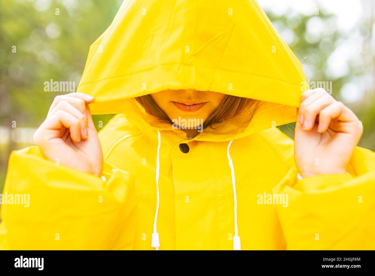 Lächelndes Mädchen im Teenageralter, das an regnerischen Tagen im Freien Regenmantel trägt Stockfoto