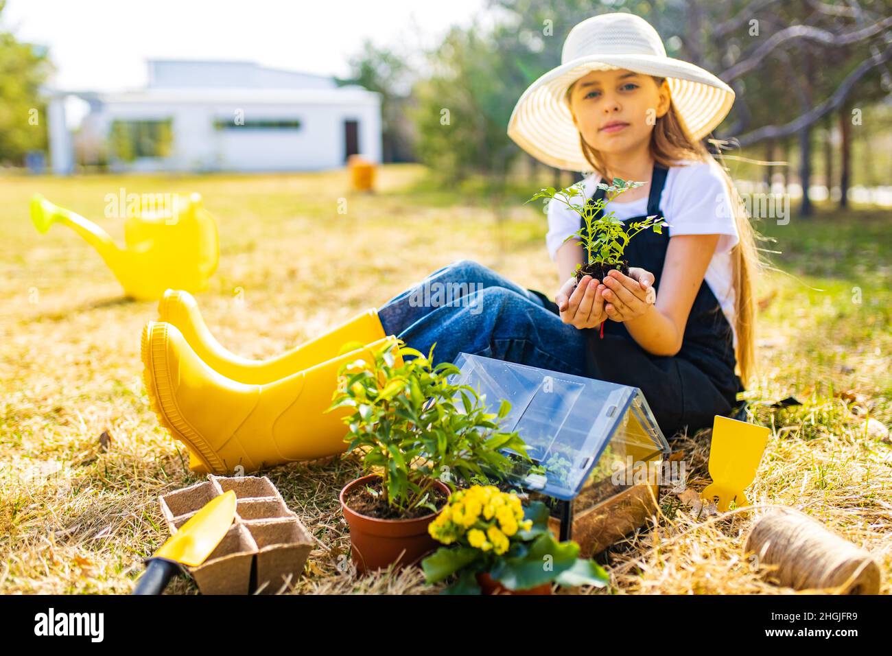 Schöne Teenager-Alter Mädchen in schwarzer Schürze und gelben Gummischuhe in Garten Natur und Pflege Stockfoto