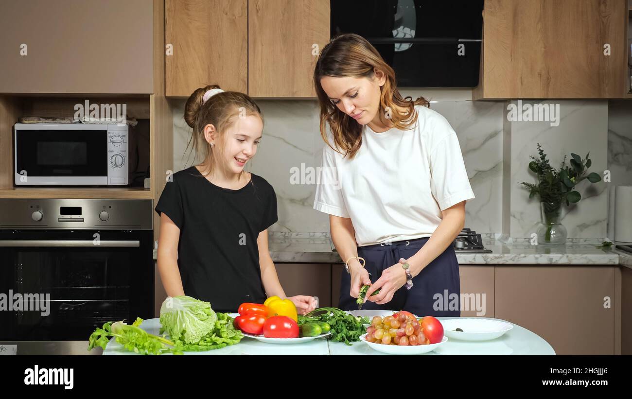 Mutter zeigt Tochter schneiden Gurken Prozess in der Küche Stockfoto