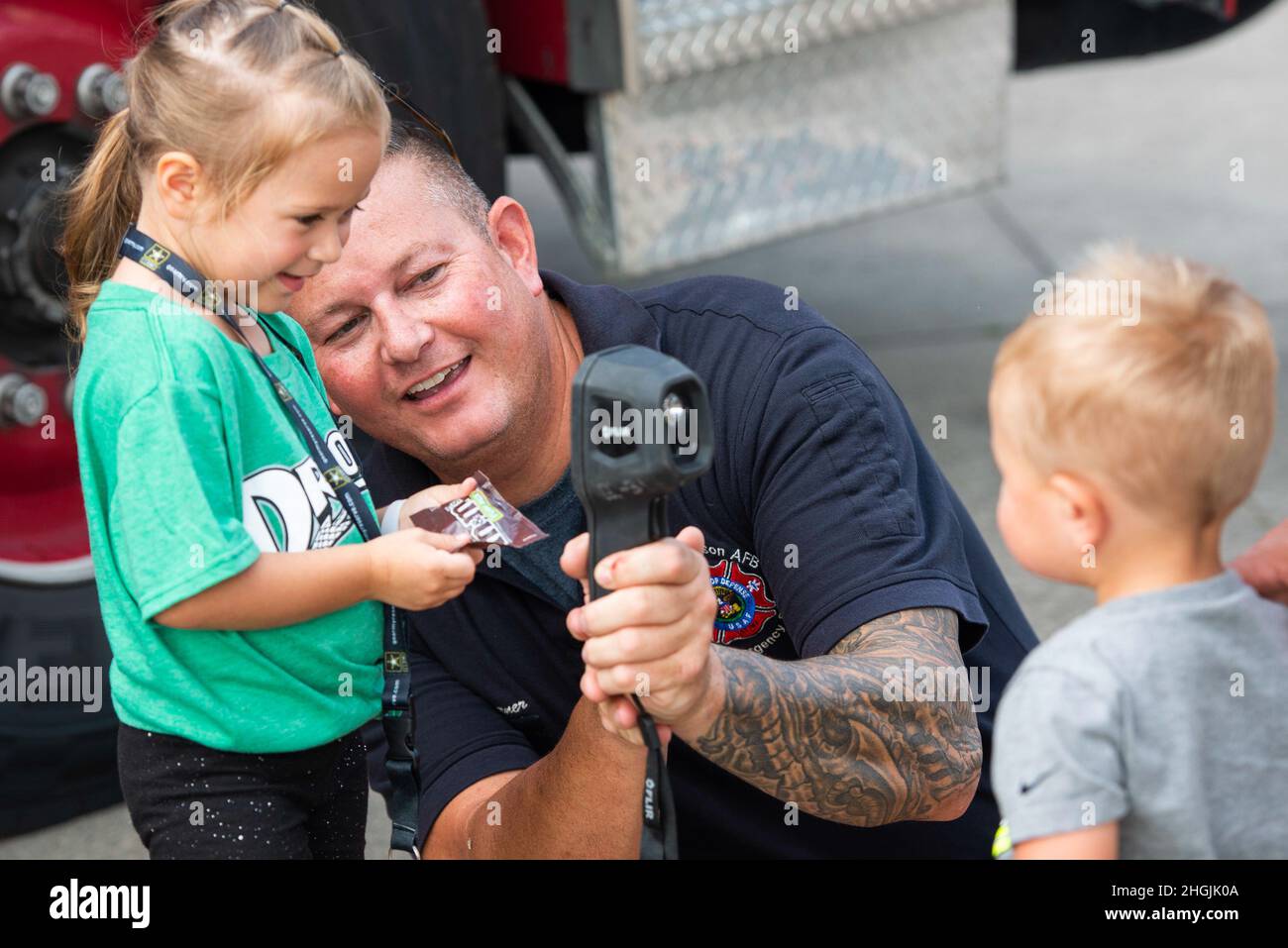 Jeff Turner, ein Feuerwehrmann mit der 788. Civil Engineer Squadron Fire Department, zeigt der dreijährigen Skyler Brandon, wie sie während einer praktischen Ausstellung außerhalb des Day Air Credit Union Ballpark im Rahmen der Dayton Dragons Hometown Heroes Night Events, 21. August, eine Wärmeablesung ihres einjährigen Bruders Wyatt ablesen kann. 2021, in Dayton, Ohio. Neben den Ausstellungen warfen die Militärs auch die zeremonielle erste Tonhöhe heraus, sangen die Nationalhymne und präsentierten die Farben während der Zeremonien vor dem Spiel. Stockfoto