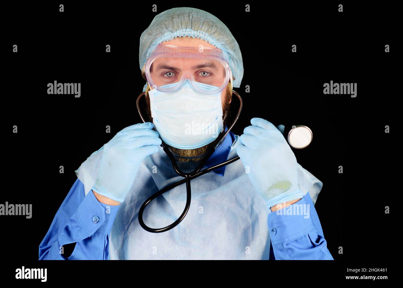 Arzt in Medizinische Kappe, Maske und Handschuhe mit Stethoskop. Arzt in Uniform und Schutzbrille. Stockfoto