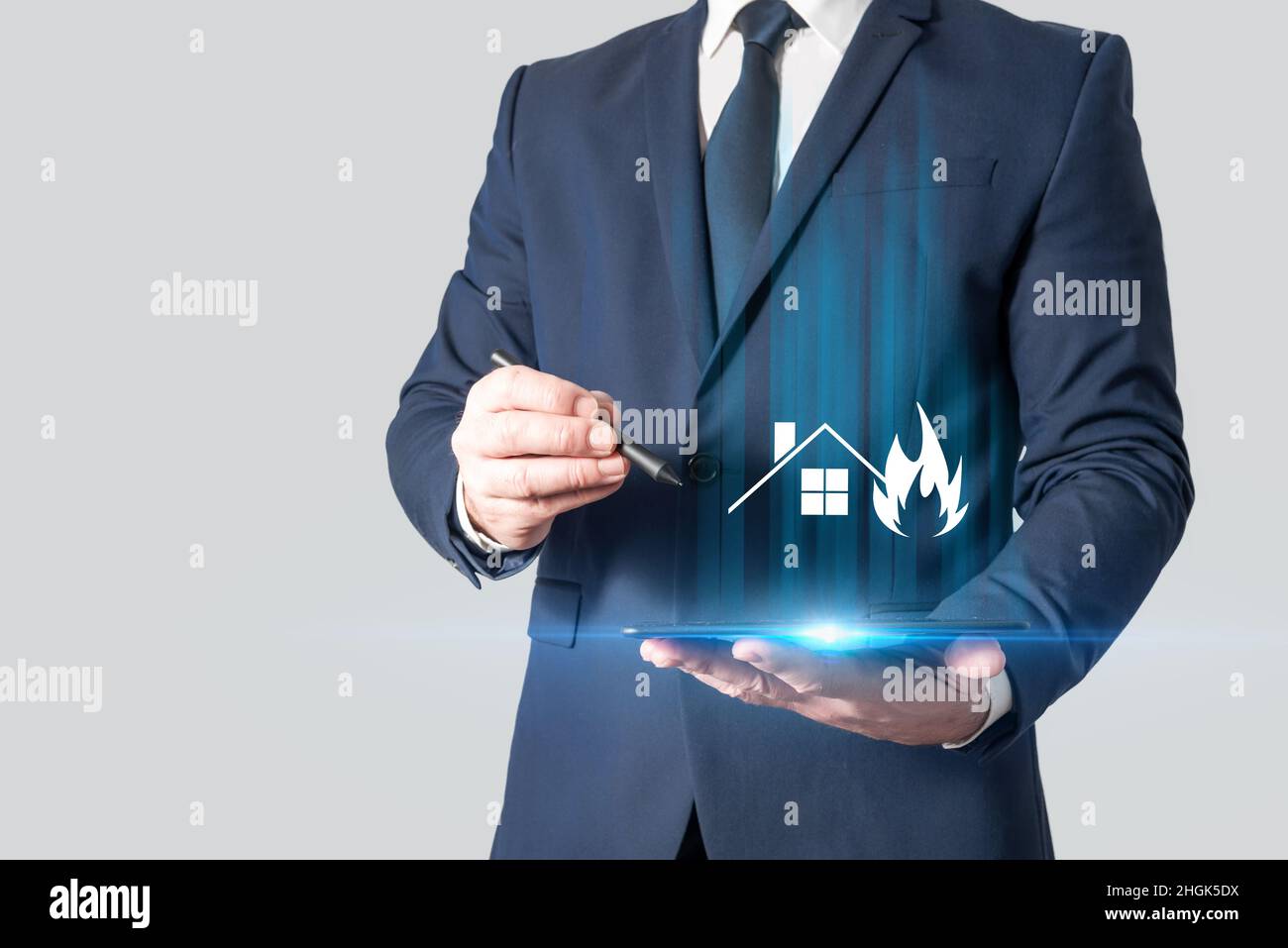 Versicherungsvertreter hält eine Tablette mit einem Bild eines brennenden Hauses. Hausversicherung. Schutz vor unvorhergesehenen Ereignissen zu Hause Stockfoto