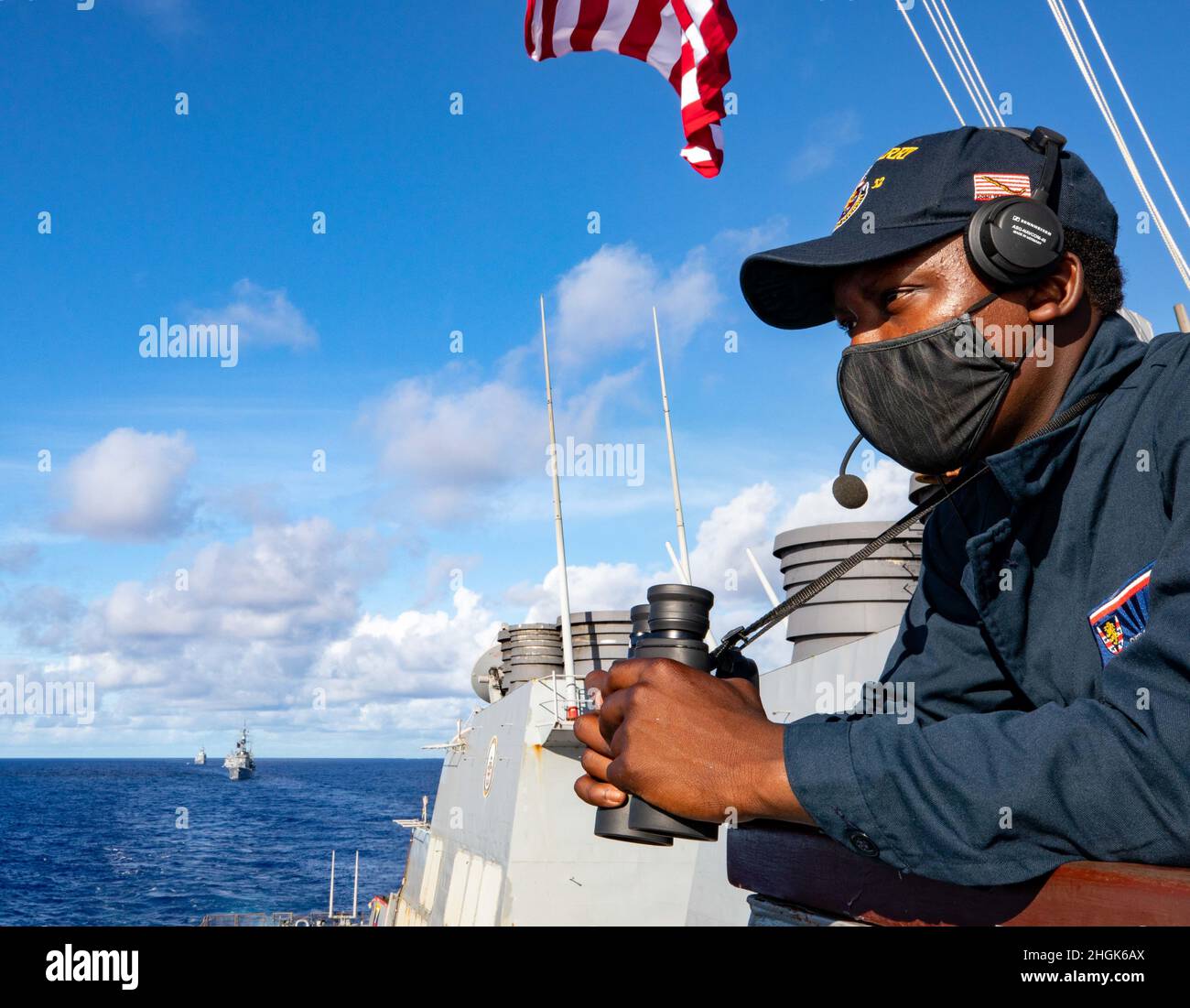 PHILIPPINISCHES MEER (Aug 28, 2021) der aus Miami stammende Seaman Gerrod Collins steht auf dem Brückenflügel des Arleigh Burke-Klasse-Lenkrakenzerstörers USS Barry (DDG 52) als HMAS Warramunga der Royal Australian Navy zusammen mit Schiffen der Japan Maritime Self-Defense Force und der Indian Navy während DER MALABAR 2021 in Formation segeln. Barry wird derzeit zur Unterstützung von Commander, Task Force (CTF) 71/Destroyer Squadron (DESRON) 15, der größten vorwärtseingesetzten DESRON der Marine und der wichtigsten Surface Force der US-Flotte der 7. Flotte eingesetzt. Stockfoto