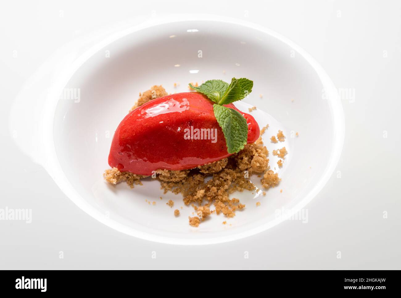 Hausgemachte Bio-Beerensorbet-Eiscreme quenelle in Form von Minzblättern auf zerbröseltem Cookie Stockfoto