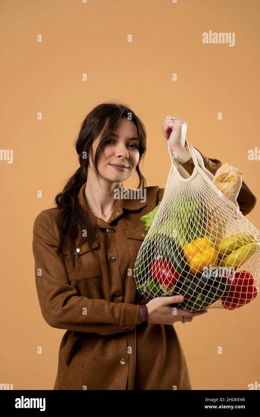 Frau zeigt eine wiederverwendbare Einkaufstasche aus Mesh voller frischer Lebensmittel. Keine Verschwendung. Ökologisch und umweltfreundlich verpackt. Leinwand und Leinen Stockfoto