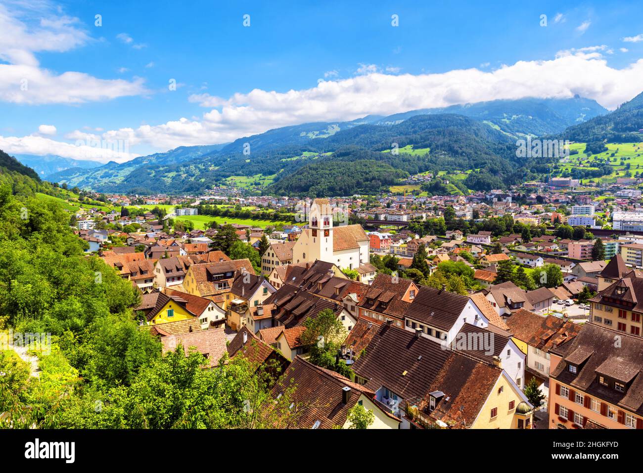 Landschaft mit Bergen und Stadt, Schweiz. Panorama der Alpenstadt im grünen Tal, landschaftlich reizvolle Aussicht auf Schweizer Gelände. Landschaft von Häusern und Gebäuden Stockfoto