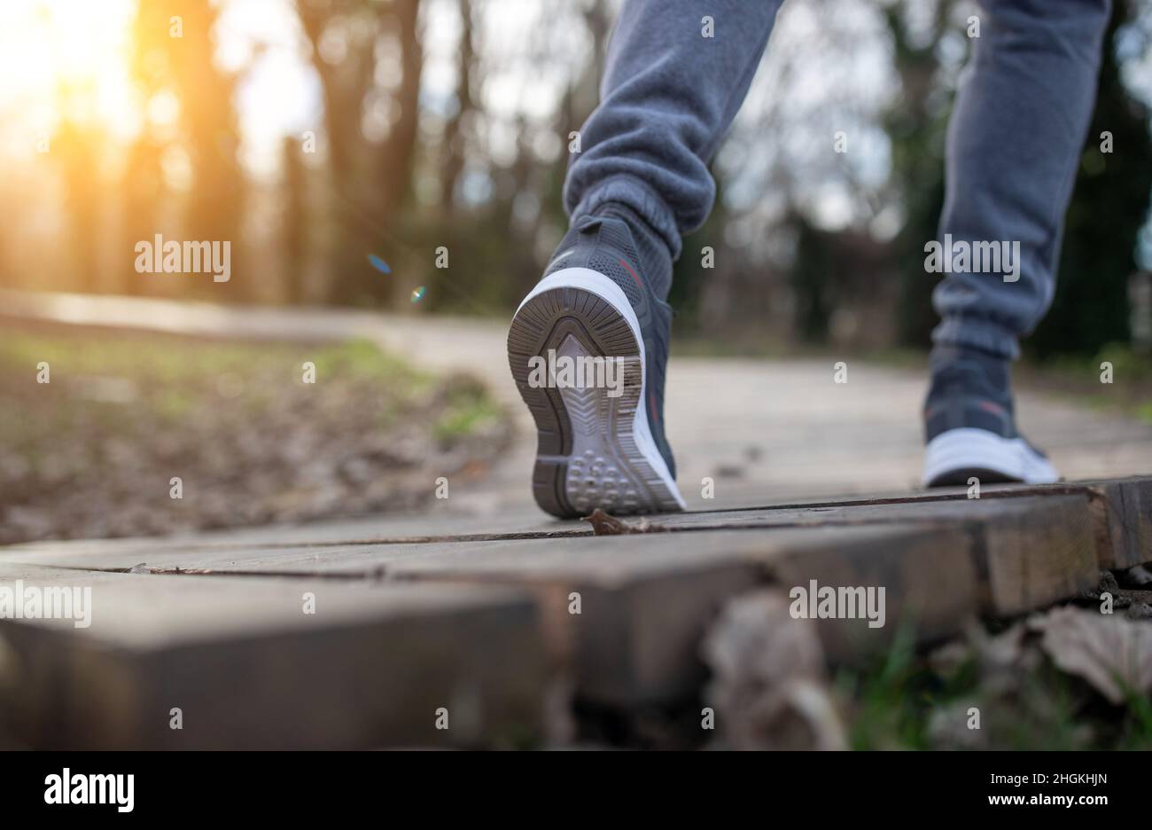 Niedriger Winkel der männlichen Beine in Sneakers Wandern oder Joggen auf Holzbahn Stockfoto